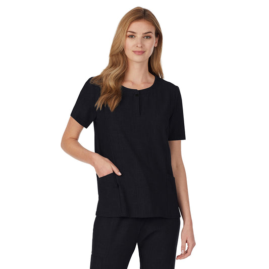 A lady wearing black short sleeve scrub henley neck top with side pockets.