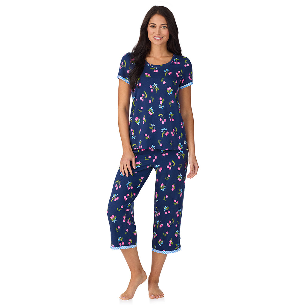 Navy Cherry Bow; Model is wearing size S. She is 5'8.5", Bust 32", Waist 25", Hips 36". @A lady wearing Cotton-Blend Short Sleeve Top with Cropped Pant 2-Pc Pajama Set in Navy Cherry Bow