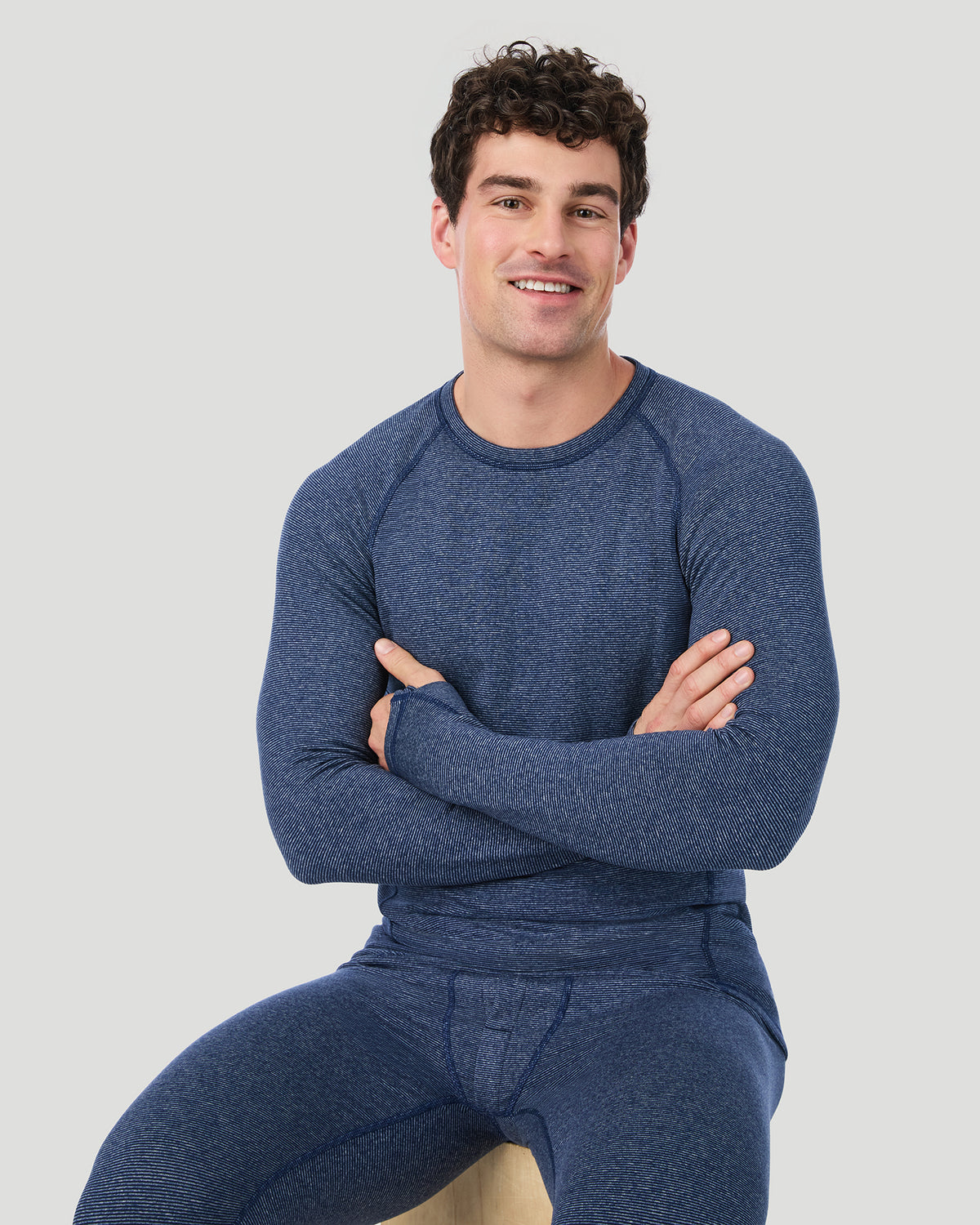 Navy Stripe; Model is wearing a size M. He is 6’2”, Waist is 32”, Inseam 32”.  @ A man wearing Navy Stripe FlexStripe Long Sleeve Crew in a front sitting pose smiling to the camera