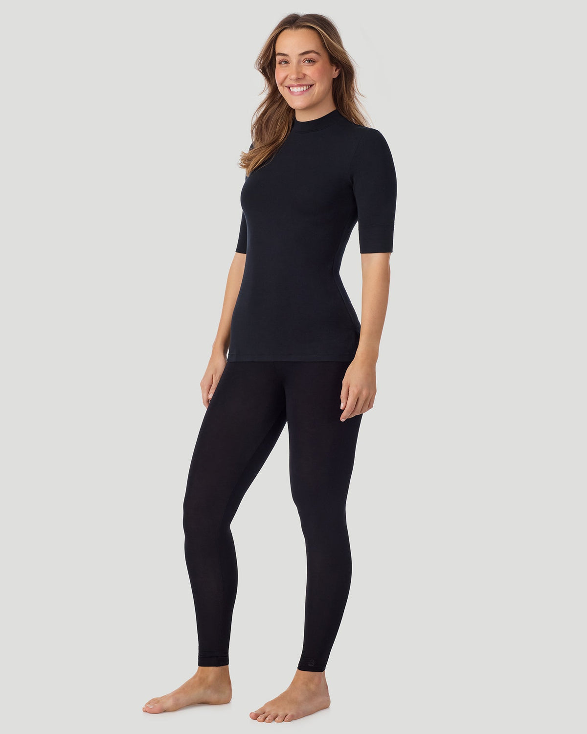 A lady wearing Softwear With Stretch Elbow Sleeve Mock Neck in black shown in a front view standing pose