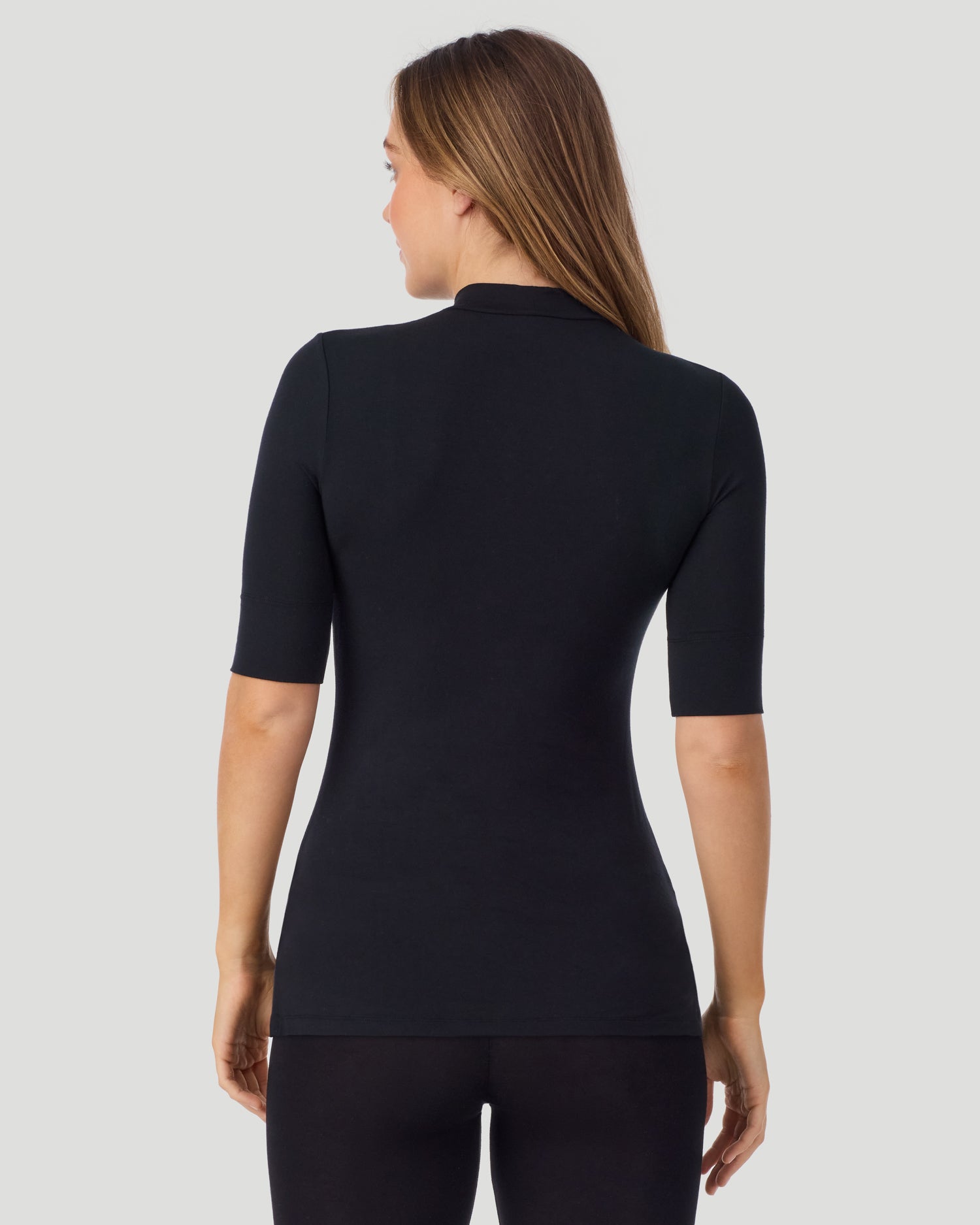 A lady wearing Softwear With Stretch Elbow Sleeve Mock Neck in black shown in a back view pose