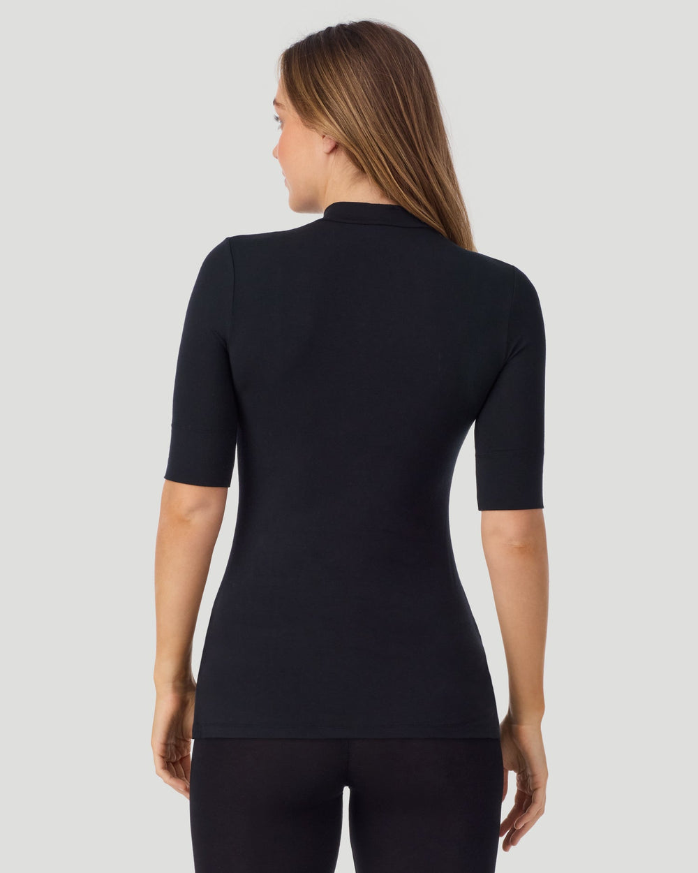 A lady wearing Softwear With Stretch Elbow Sleeve Mock Neck in black shown in a back view pose
