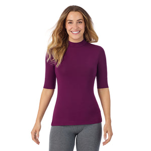A lady wearing a dark purple elbow sleeve mock neck.