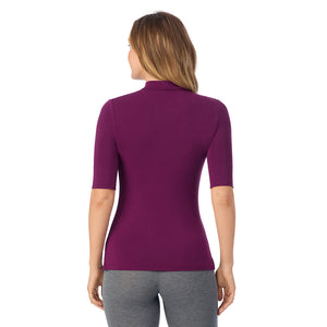 A lady wearing a dark purple elbow sleeve mock neck.