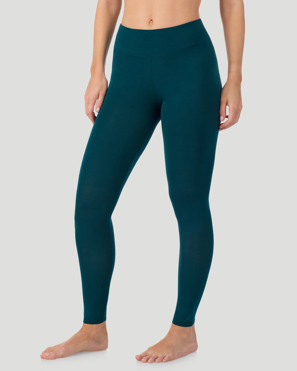 A lady wearing Softwear With Stretch High Waist Legging in deep emerald posing in a front view side angle position