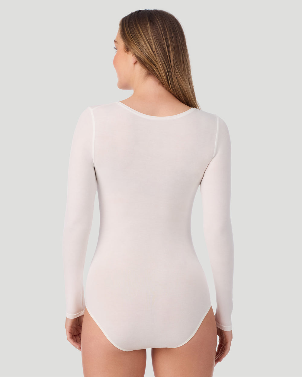 A lady wearing Softwear With Stretch Long Sleeve Bodysuit in ivory shown in a back view pose