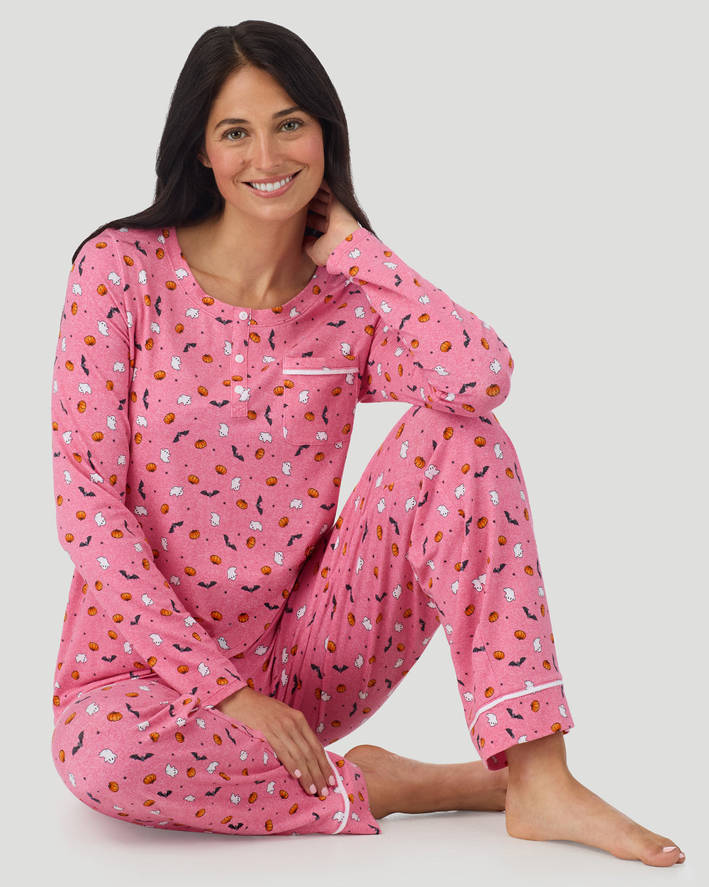 A lady wearing Cotton-Blend Long Sleeve Top and Long Pant Pajama Set in Pink Halloween sitting down