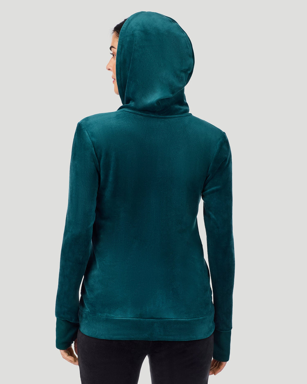 A lady wearing Stretch Velour Full Zip Hoodie in deep emerald shown in a back view pose