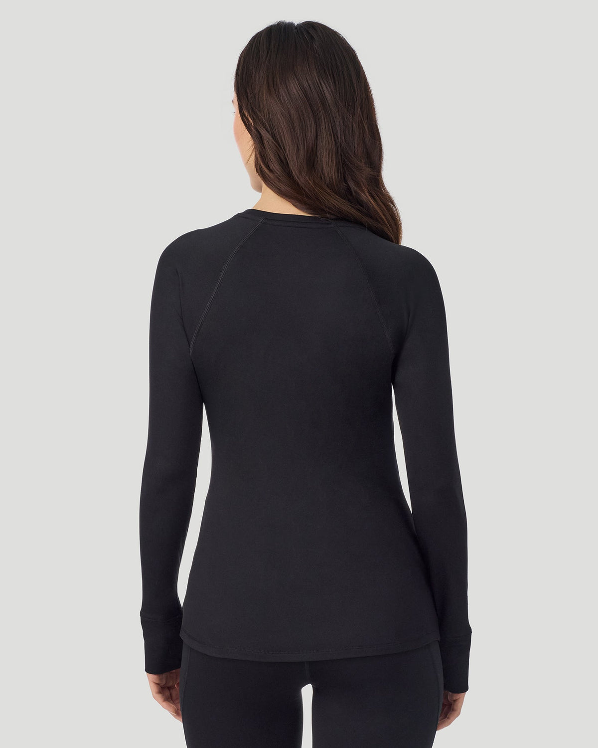 A lady wearing Thermawear Long Sleeve Raglan Crew in black shown in a back view pose