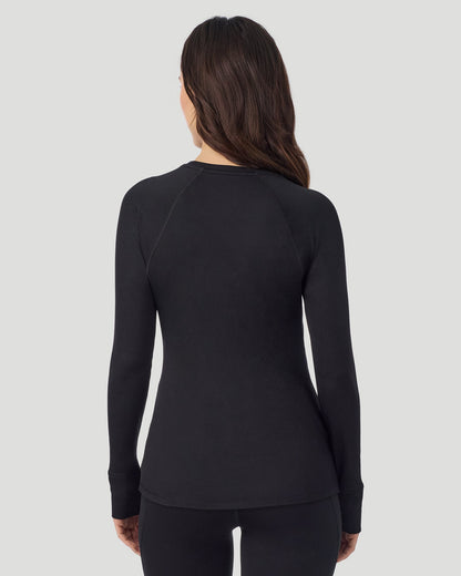 A lady wearing Thermawear Long Sleeve Raglan Crew in black shown in a back view pose