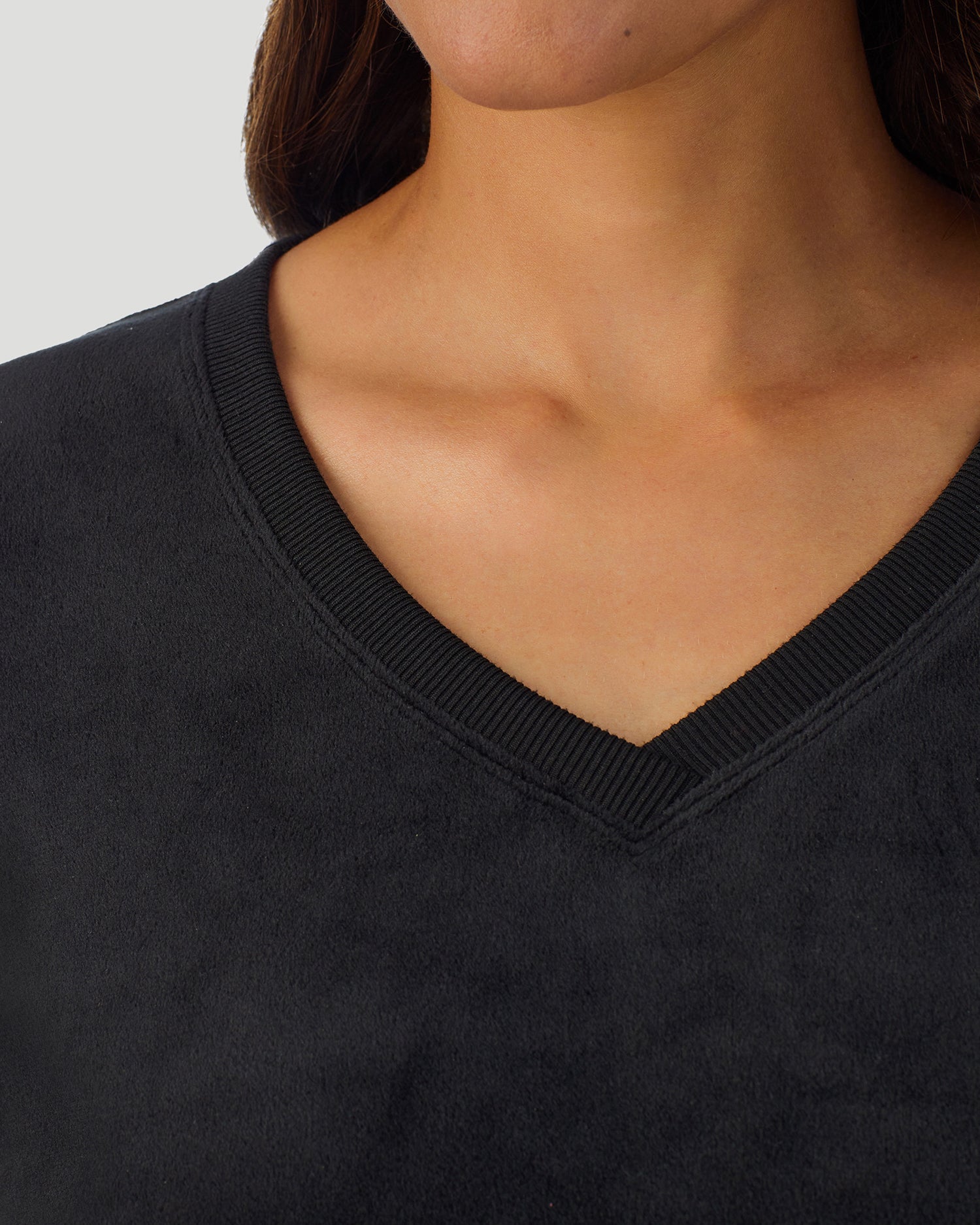 A lady wearing Stretch Velour Long Sleeve V-Neck in black shown in a front view detail close up shot