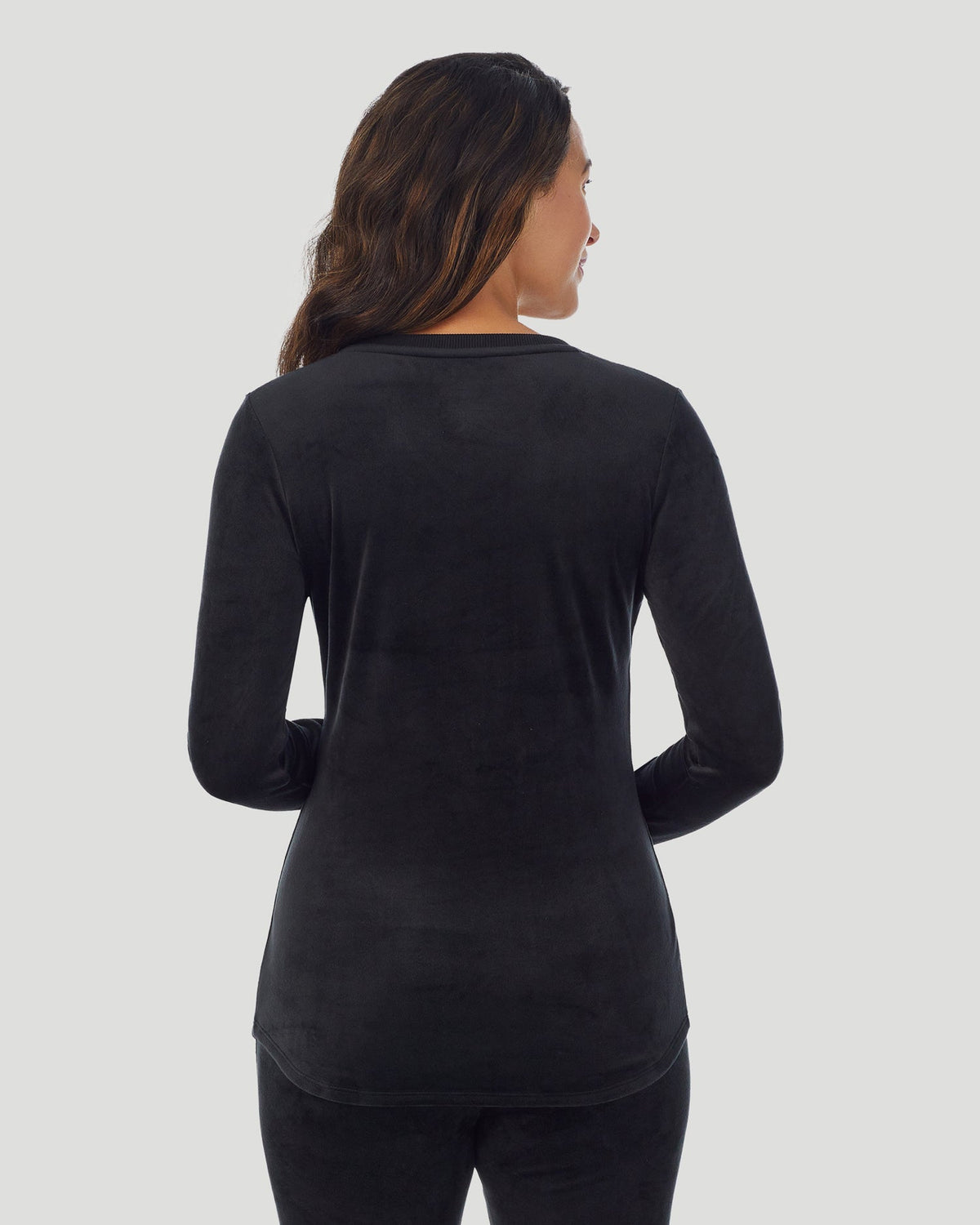 A lady wearing Stretch Velour Long Sleeve V-Neck in black shown in a back view pose
