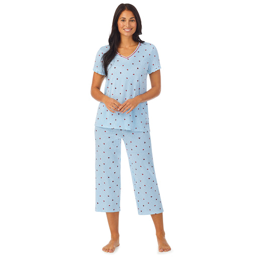 A lady wearing short sleeve top with cropped pant pajama set with blue stripes and ladybug print