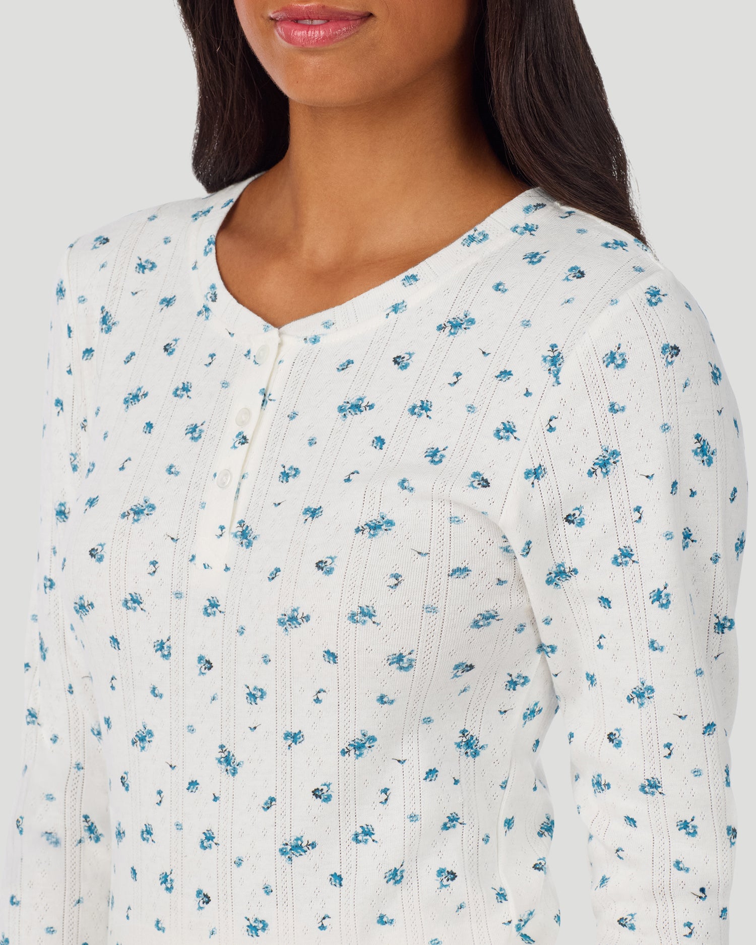 A lady is wearing Blue Ditsy Cotton Pointelle Long Sleeve Henley in a front view detail close up look
