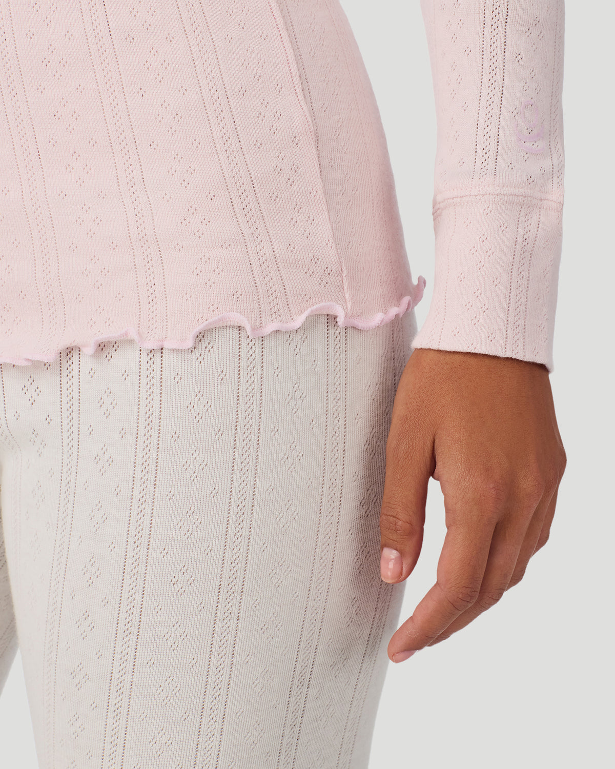 Pretty Rose; Model is wearing a size S. She is 5’7”, Bust 32”, Waist 25”, Hips 34”. @A lady is wearing Pretty Rose Cotton Pointelle Long Sleeve Henley in a front view close up look of the sleeve