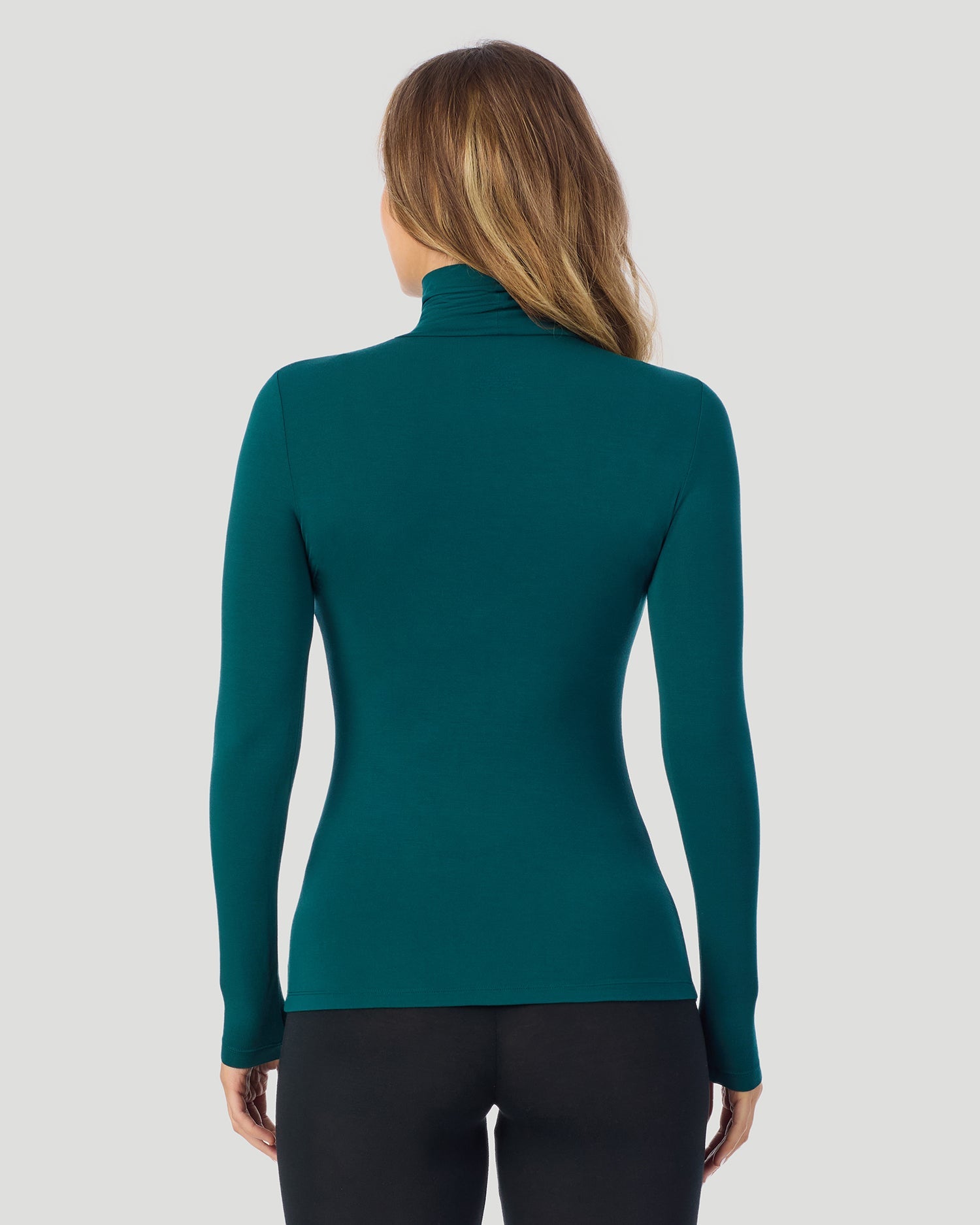 A lady wearing Deep Emerald Softwear With Stretch Long Sleeve Turtleneck top in a back pose