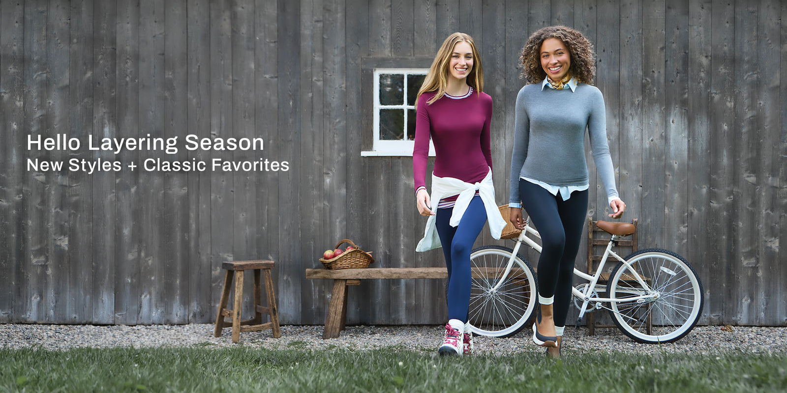 Hello Layering Season: New Styles + Classic Favorites. Two women in layered tops and leggings walk past a rustic barn.