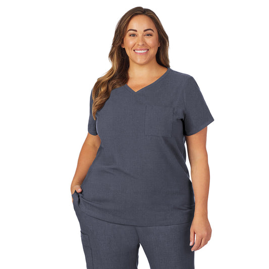 A lady wearing navy heather scrub v-neck top with chest pocket plus.