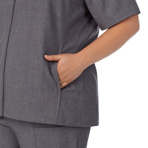 A lady wearing charcoal heather scrub vest plus.