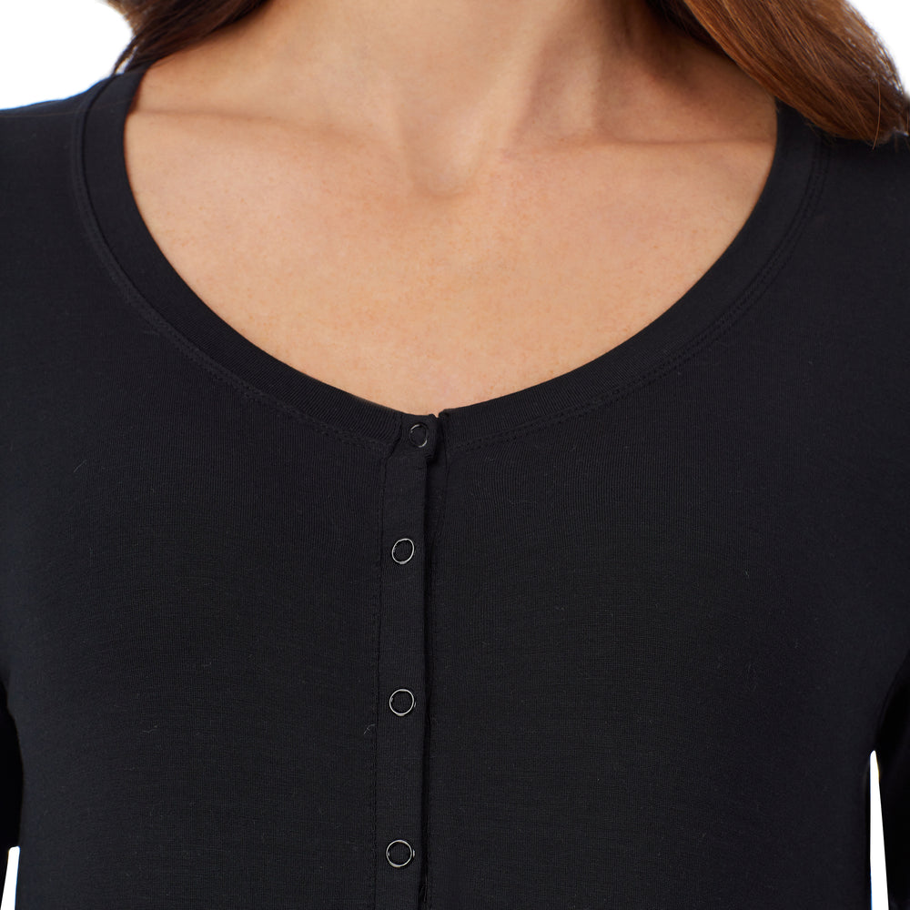 A lady wearing a black long sleeve maternity snap front henley top. #Model is wearing a maternity bump.