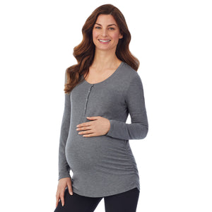 A lady wearing a charcoal heather long sleeve maternity snap front henley top. #Model is wearing a maternity bump.