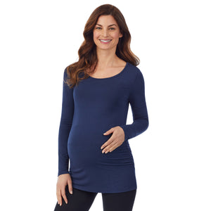 A lady wearing a dress blue long sleeve maternity ballet neck top. #Model is wearing a maternity bump.