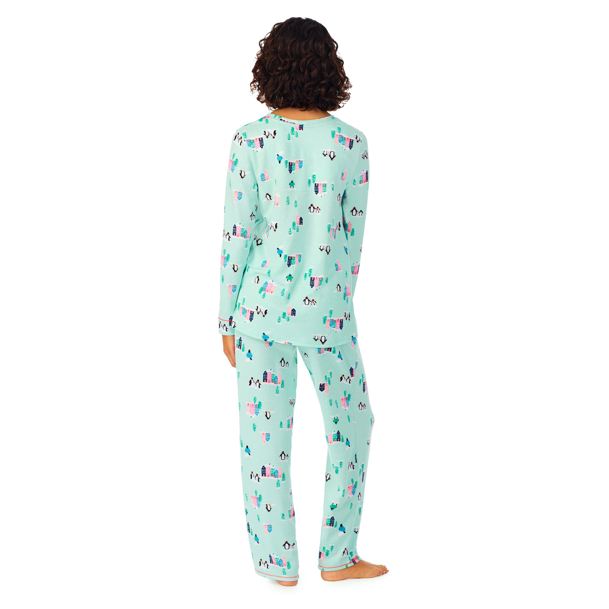 A lady wearing a teal long sleeve pajama set with penguins pattern.