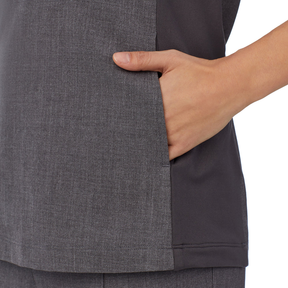 A lady wearing charcoal heather scrub split neck top.